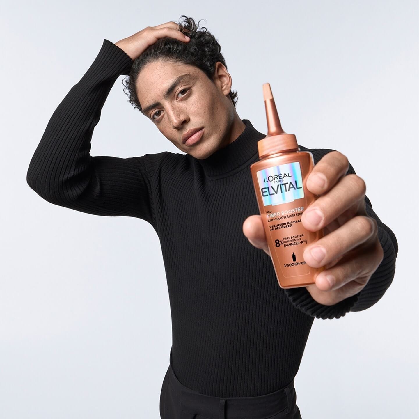 Mann hält Elvital Fiber Booster Anti-Haarverlust Serum in der Hand